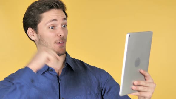 Online Video Chat on Tablet By Casual Young Man on Yellow Background