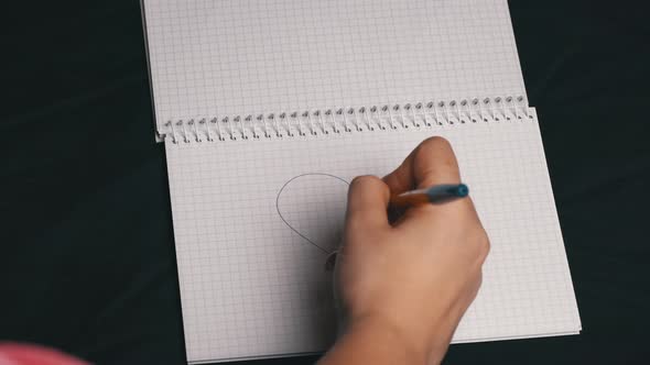 Girl Draws a Heart and Tears Out a Page From a Notebook