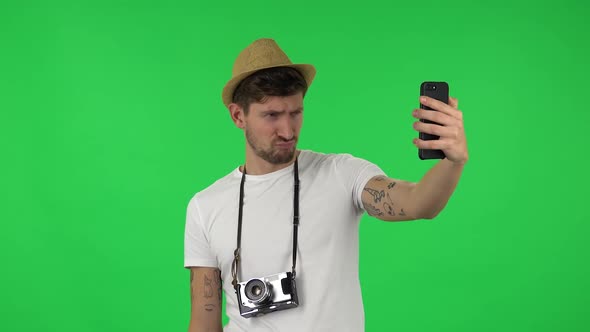 Portrait of Confident Guy Is Making Selfie on Mobile Phone Then Looking Photos. Green Screen