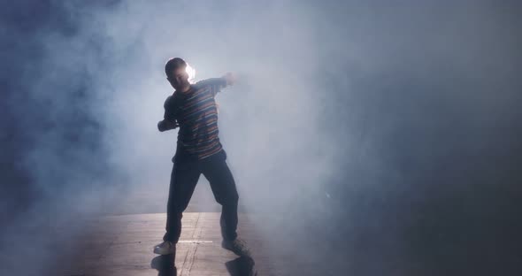 Young female dancer performing hip hop dance in slow motion with light and smoke background