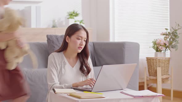 Busy mother working with computer laptop and her daughter playing makes noise disturbs mom work