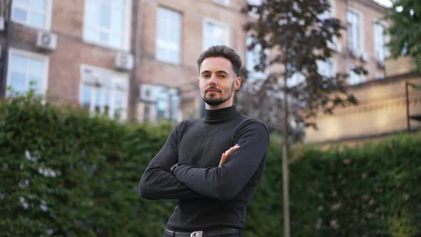 Portrait of Ambitious Confident Caucasian Young Man Crossing Hands Looking at Camera