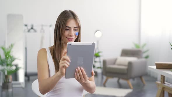 Portrait of Young Cute Woman Getting Good News From Her Tablet Sitting at Home