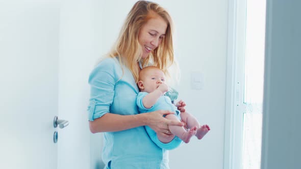 Portrait of Happy Mother Walking in the Room with Her Infant Kid