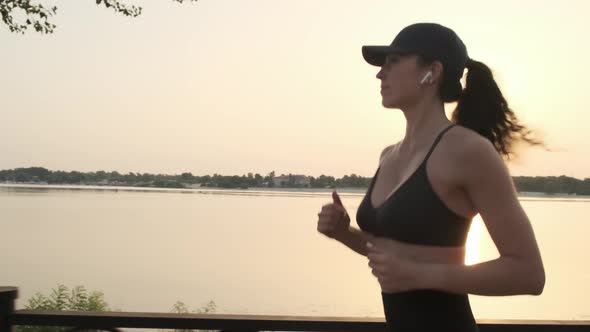 Young Woman Running and Listening to Music Against Morning Sun Closeup