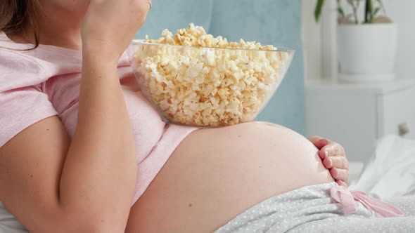 CLoseup of Pregnatn Woman Watching TV and Eating Popcorn From Big Bowl