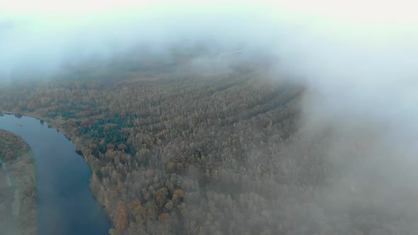 Flying Through a Haze of Clouds To a Stunning Autumn Landscape with a Winding River in the Forest