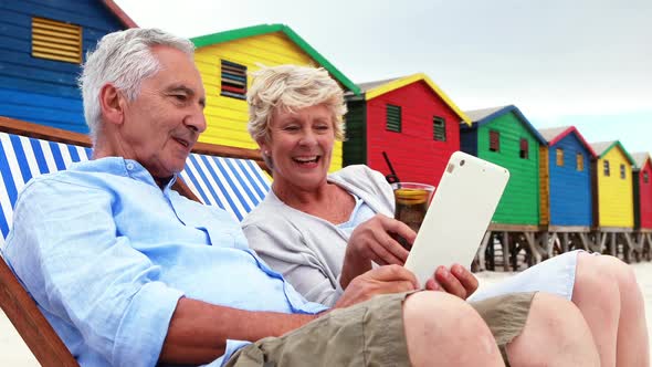 Senior couple using digital tablet at the beach