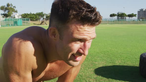 Smiling fit shirtless caucasian man recovering after exercising outdoors