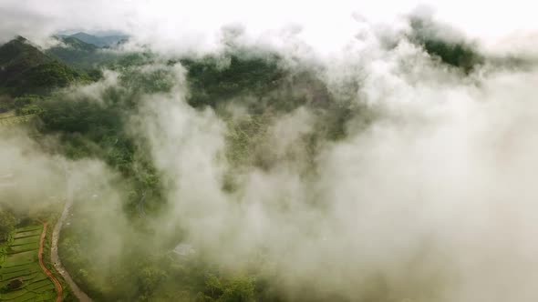 Aerial view flying above lush green tropical rain forest mountain with rain cloud cover during the r