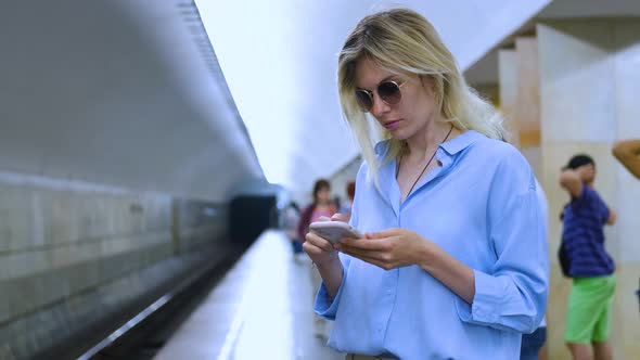 woman with smartphone waiting for subway train