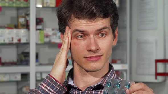 Young Man Having Headache Holding Pills