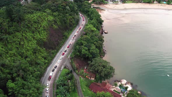 Traffic jam at end of day in coastal road, descent to Ubatuba beach, Brazil. Aerial forward