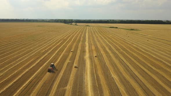 Aerial view: Tractor producing hay bales in a wheat field. Agriculture area