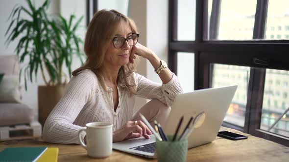 Businesswoman Using Laptop and Sitting at Table in Home Office During Pandemic