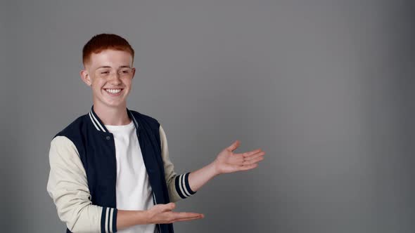 Redhead boy looking at camera and pointing on copy space. Shot with RED helium camera in 8K.