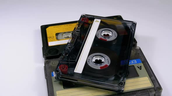 Three Vintage Audio Cassettes Rotate on White Background