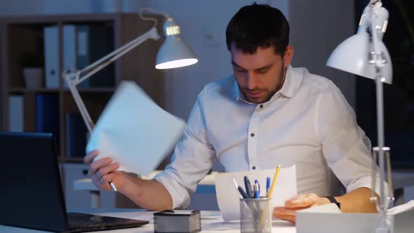 Businessman with Papers and Laptop at Night Office 26