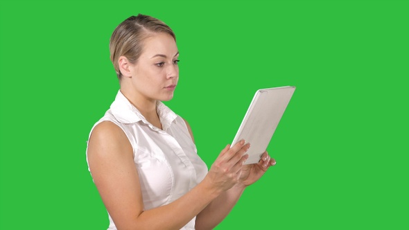 Pretty Woman Standing and Using a Tablet on A Green Screen