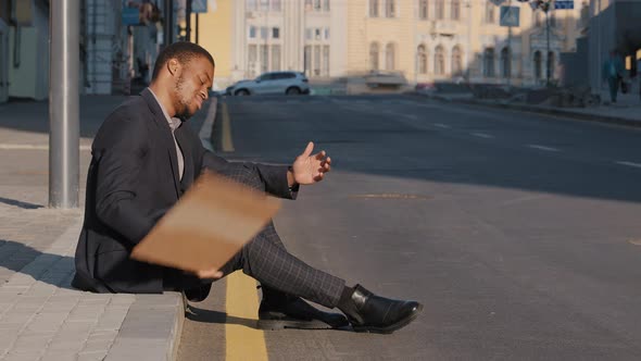 Desperate Disgruntled African American Millennial Student Wearing Suit Sitting on Steps Outdoors