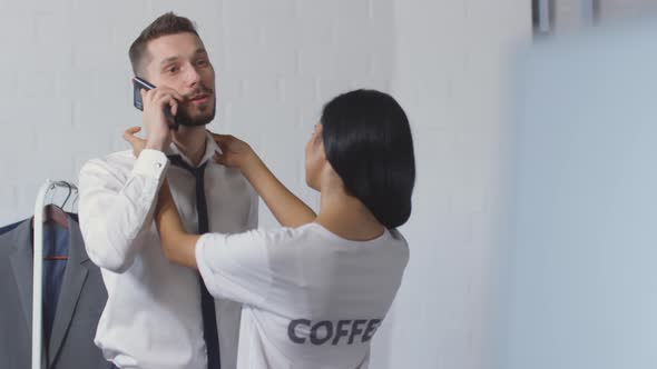 Loving Wife Helping Husband with Necktie while He Speaking on Phone