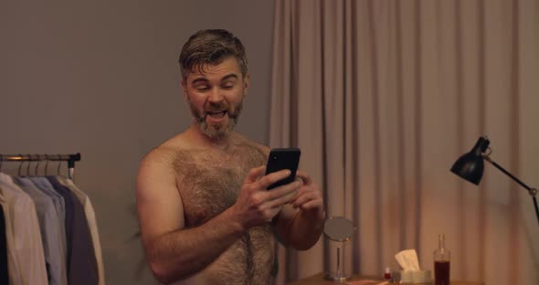 Close Up View of Bearded Man Getting Good News on His Smartphone and Rejoicing, Emotional Mature Guy