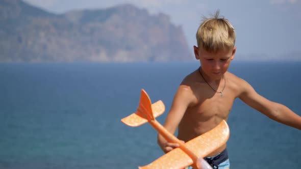 Boy with a Toy Airplane in His Hands on the Background of the Sea