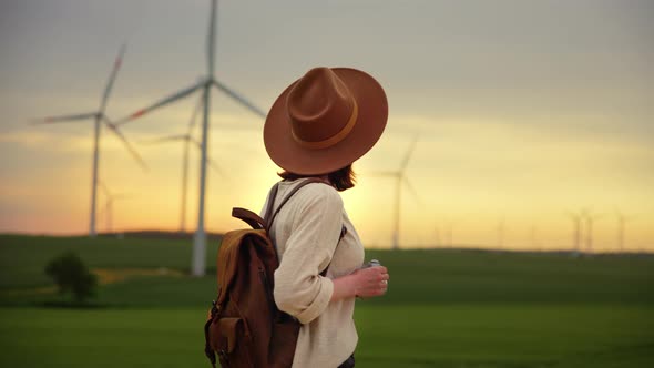 Young girl with a retro camera looking at a wind farm in a field