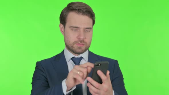 Young Businessman Browsing Smartphone on Green Background