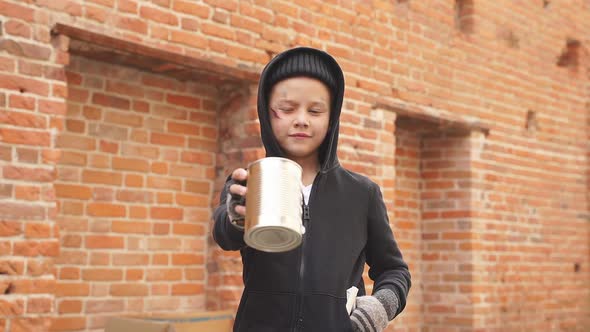Street Boy Holds Out a Tin Can for Money in Street