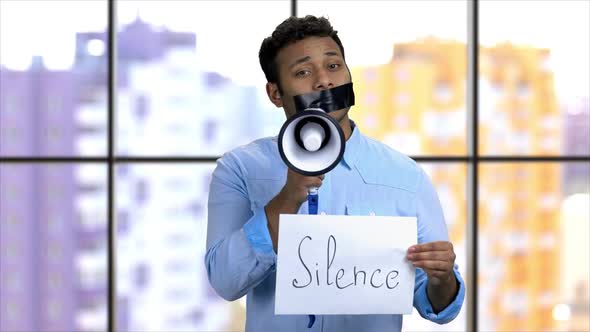 Darkskinned Activist with Taped Mouth Trying To Speak in Megaphone