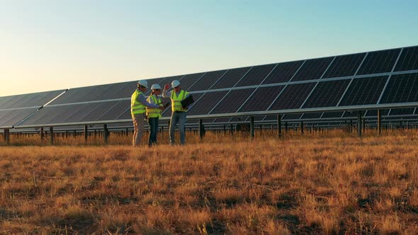 Three Solar Energy Specialists Having a Discussion on a Solar Farm