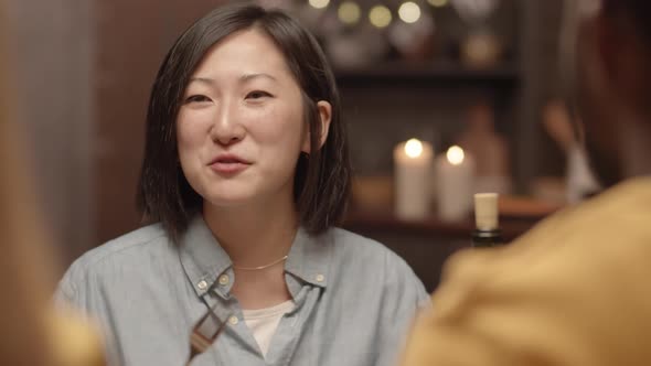 Asian Woman Eating and Talking at Dinner Party