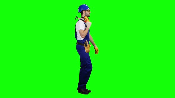 Man Builder with a Hammer in His Hands Goes To the Construction Site. Green Screen. Side View