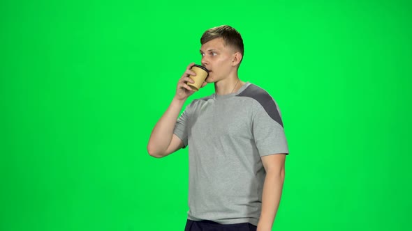 Man Is Walking and Drinking Coffee From a Paper Cup