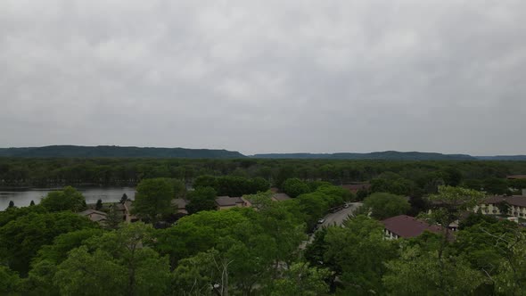 Up and over the tree tops to  landscape view of Mississippi River with residential homes