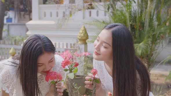 Two Girls Smelling Red Flowers