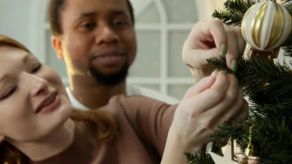 A Couple of People of Different Races Decorate the Tree