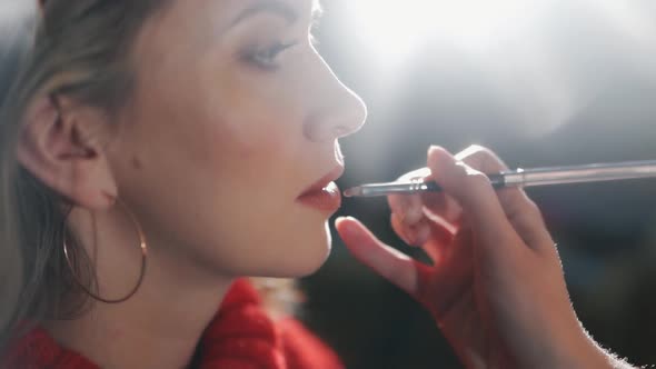 Female Make-up Artist Apply Red Lipstick with Brush on a Client’s Lips, Close-up.