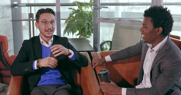 Businesspeople European and African Talking While Sitting in Chair in Office