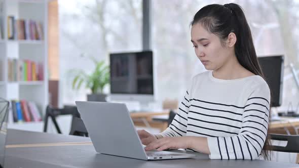 Young Asian Woman Reacting To Loss on Laptop in Office 