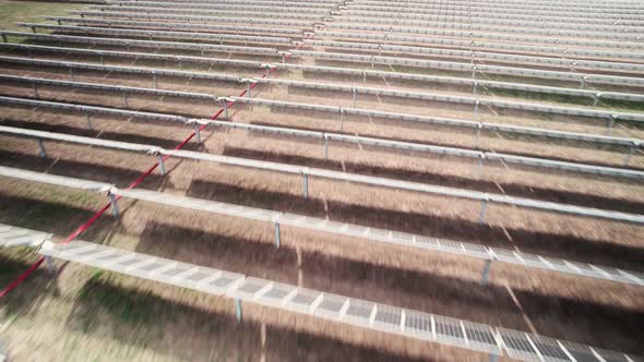 Flying quickly over horizontal rows of carbon neutral solar photovoltaic panels, green energy