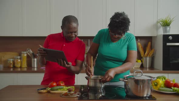 Elderly Couple Following Online Recipe Cooking in Kitchen