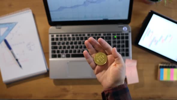 Man working in office throws bitcoin in hand in slow motion and catches it in palm