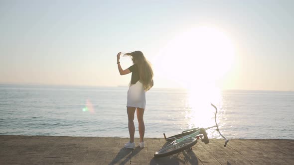 Young Attractive Woman with Long Hair is Having a Good Time on Sea at Sunset or Sunrise