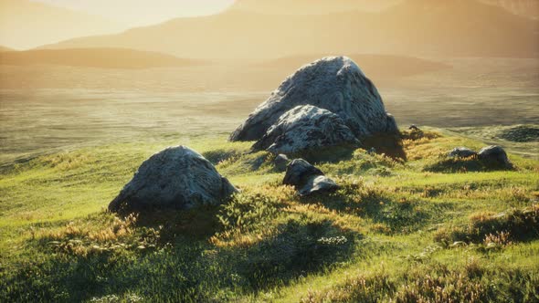 Meadow with Huge Stones Among the Grass on the Hillside at Sunset