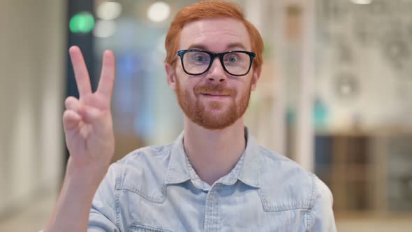 Appreciative Young Redhead Man Showing Victory Sign