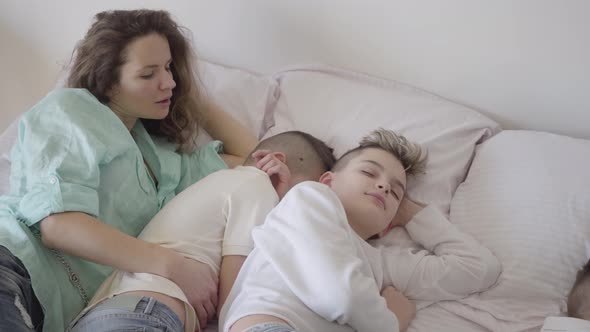 Portrait Young Mother with Her Teen Sons Sleeping Together in the Big Bed