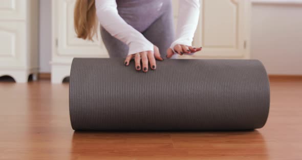 5 D4 Close-up of attractive white woman rolling out her red and grey yoga mat. health care concept