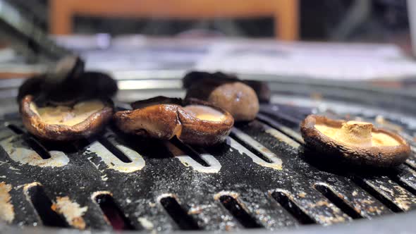 The Cook Prepares Mushrooms on Korean BBQ Grill Plate